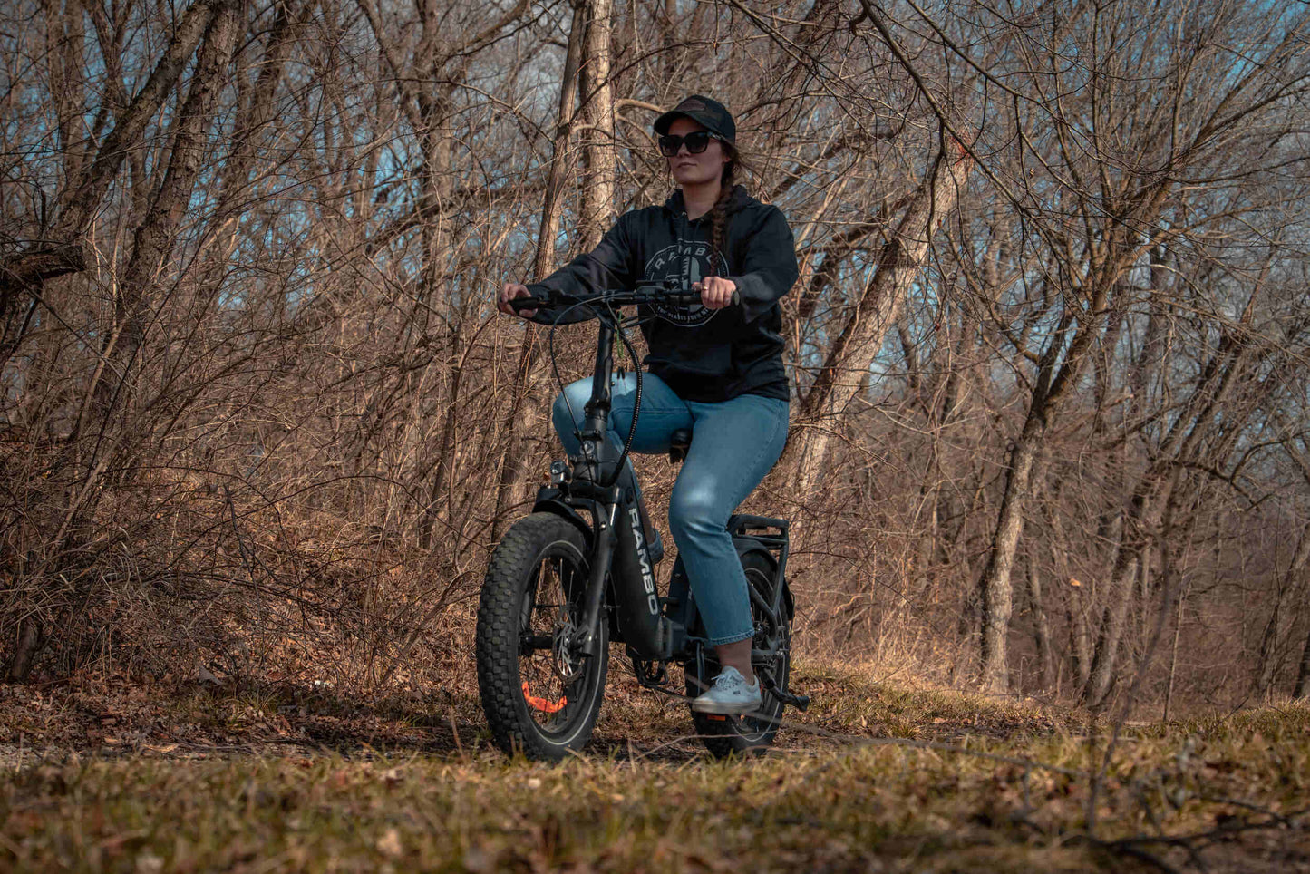 Person riding a Rambo Bikes RANGER Folding eBike on a forest trail, showcasing its rugged design and fat tires.