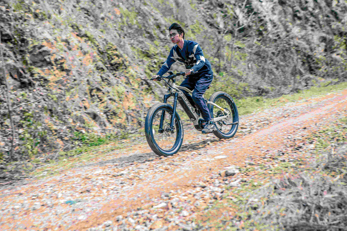 EUNORAU Specter-S 3.0 electric fat tire e-bike rider riding off-road on a dirt trail, showcasing the sturdy build and design of the bike.