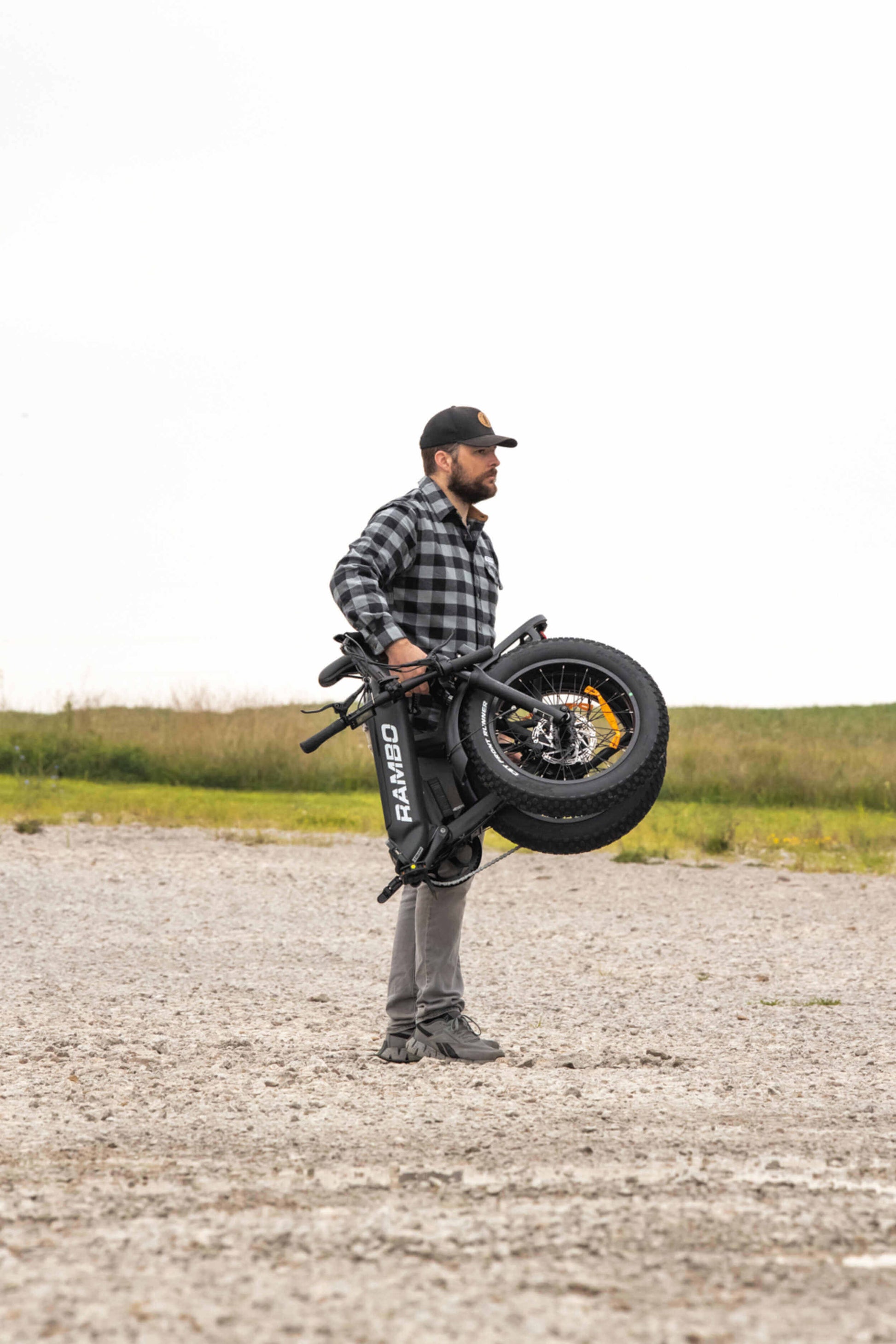 Person lifting the Rambo Bikes RANGER Folding eBike, demonstrating its portability and rugged design.