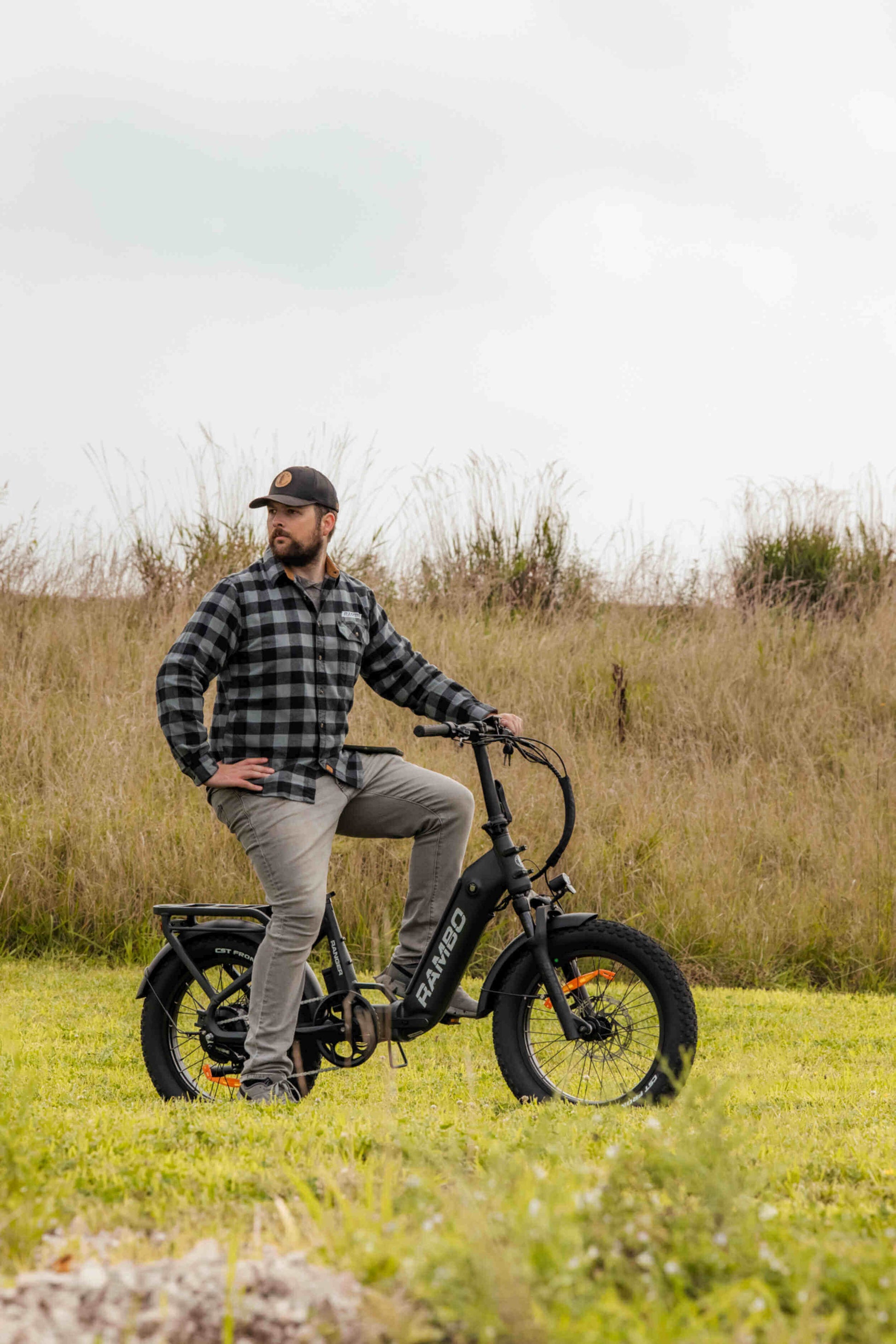 Rambo Bikes RANGER Folding eBike showcased in a grassy field with a rider in casual attire.