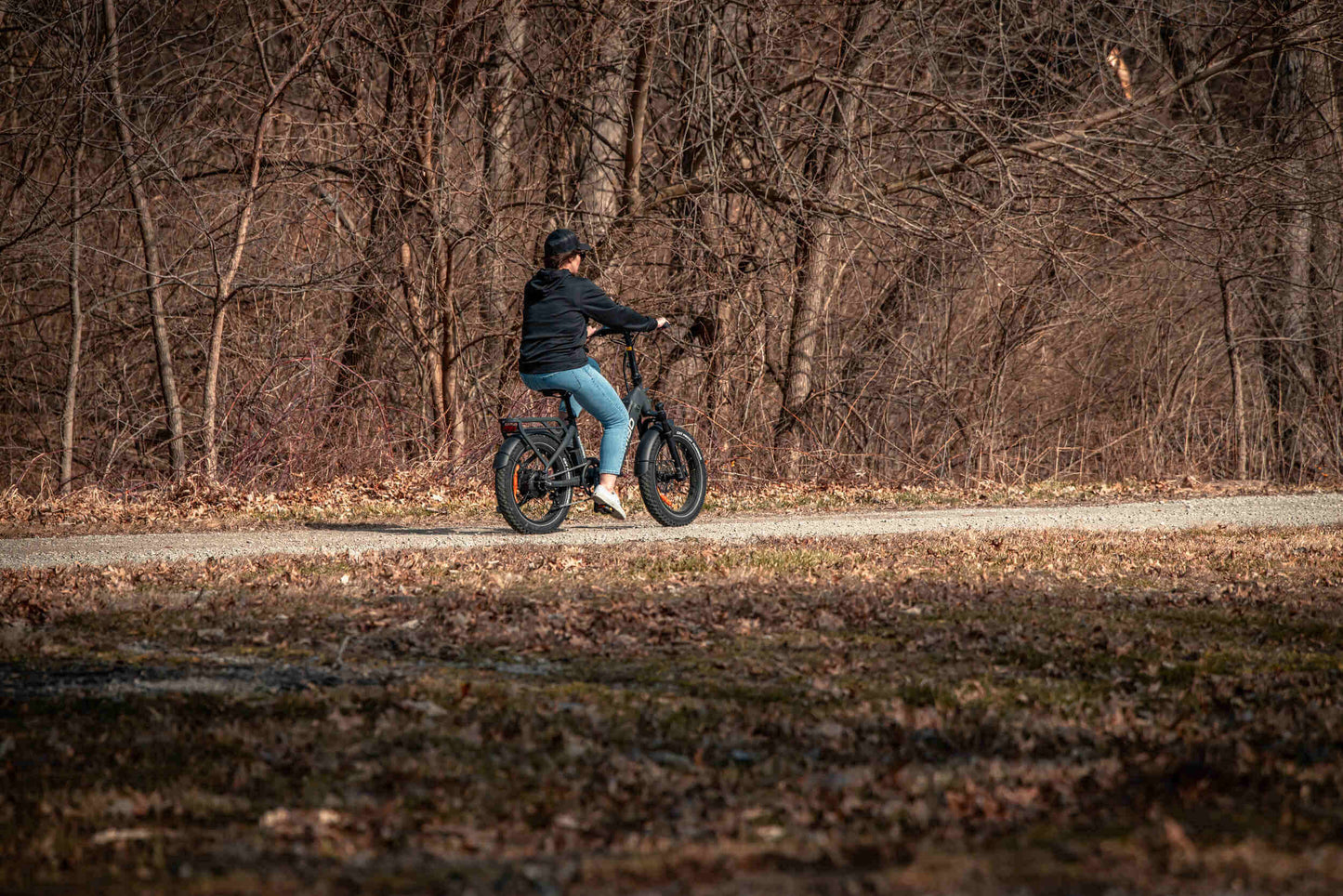 Rider enjoying a Rambo Bikes RANGER Folding eBike on a gravel path surrounded by trees.