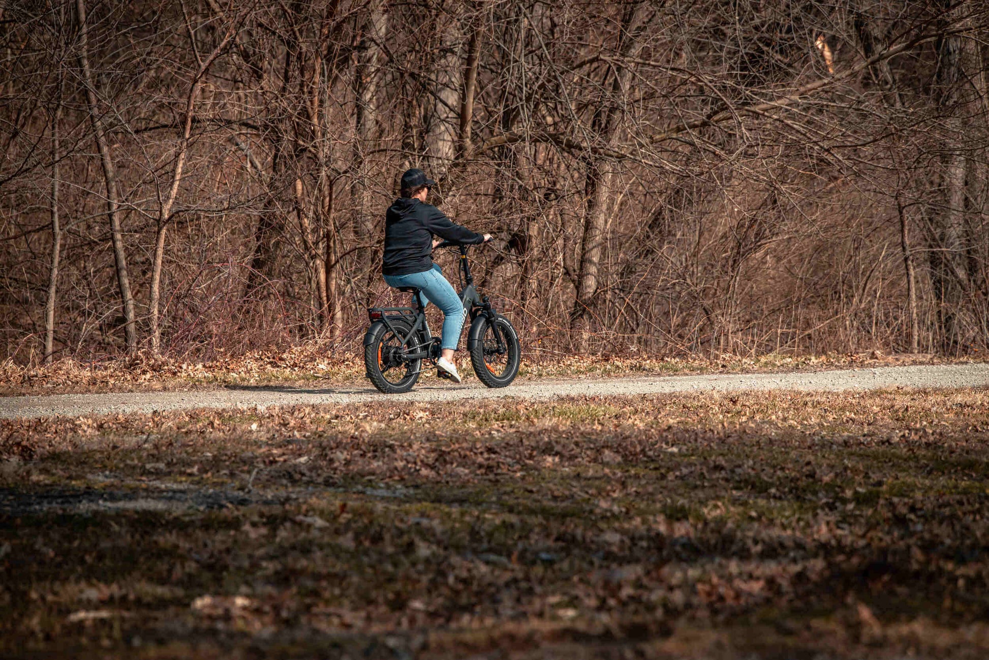 Rider enjoying a Rambo Bikes RANGER Folding eBike on a gravel path surrounded by trees.