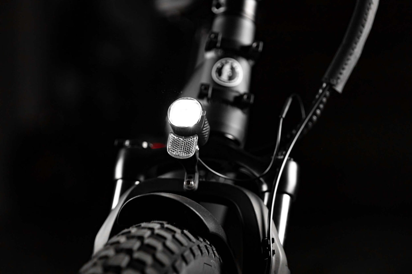 Close-up of the front light on a folding eBike, highlighting the rugged design and fat tire.