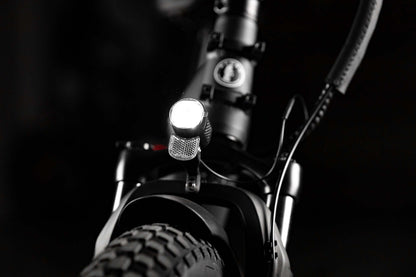 Close-up of the front light on a folding eBike, highlighting the rugged design and fat tire.