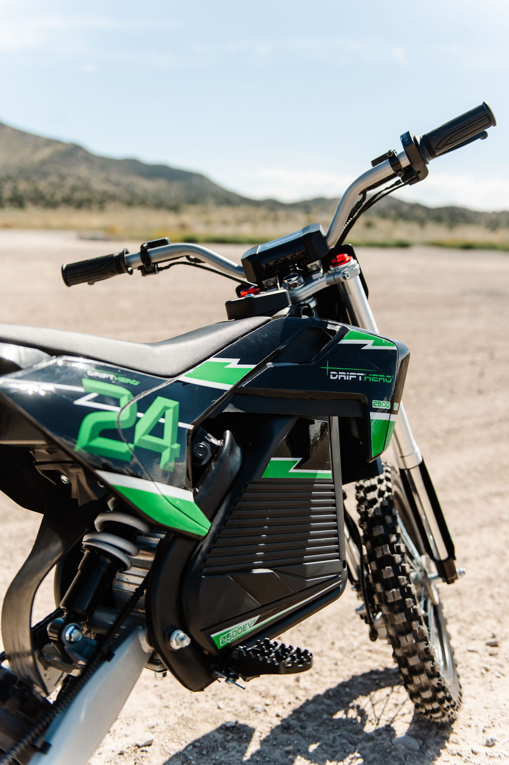 Close-up of a Drift Hero USA 2500W Electric Dirt Bike with green and black design on a dirt track