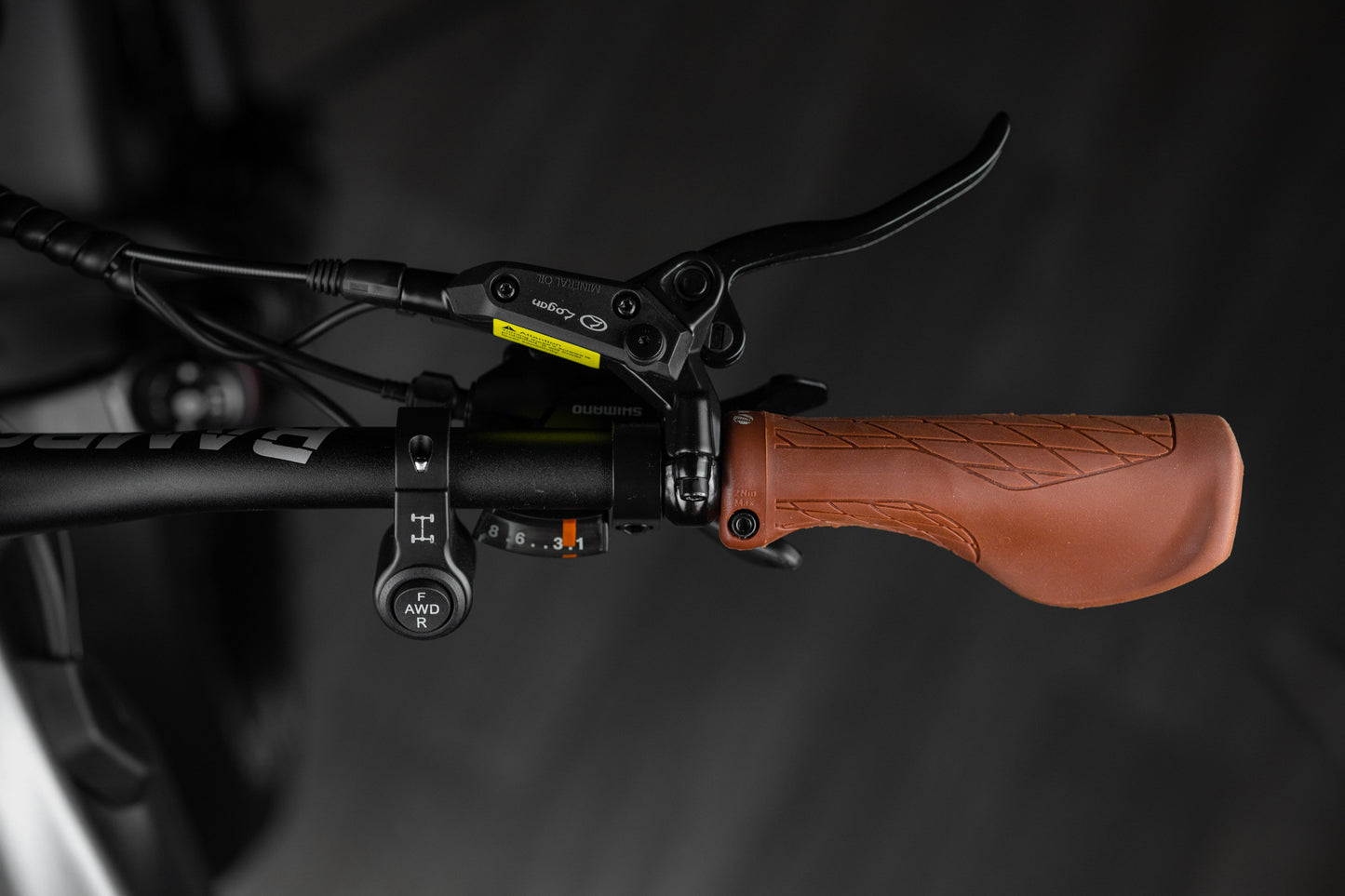 Close-up of Rambo Bike Hellcat 2.0 AWD Electric Bikes right handlebar with brake lever, gear shifter and al wheel drive controls on a black background