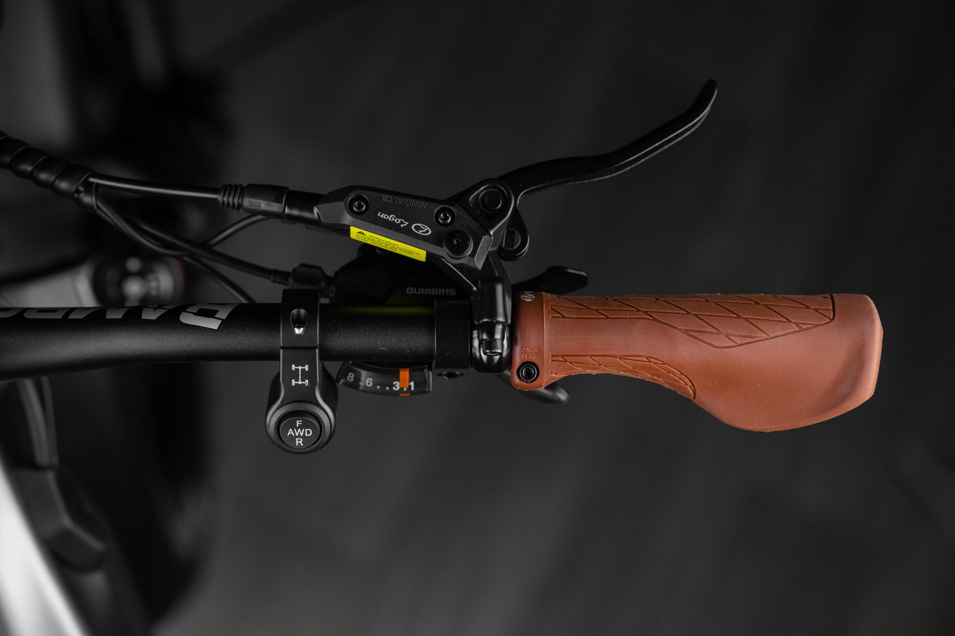 Close-up of Rambo Bike Hellcat 2.0 AWD Electric Bikes right handlebar with brake lever, gear shifter and al wheel drive controls on a black background
