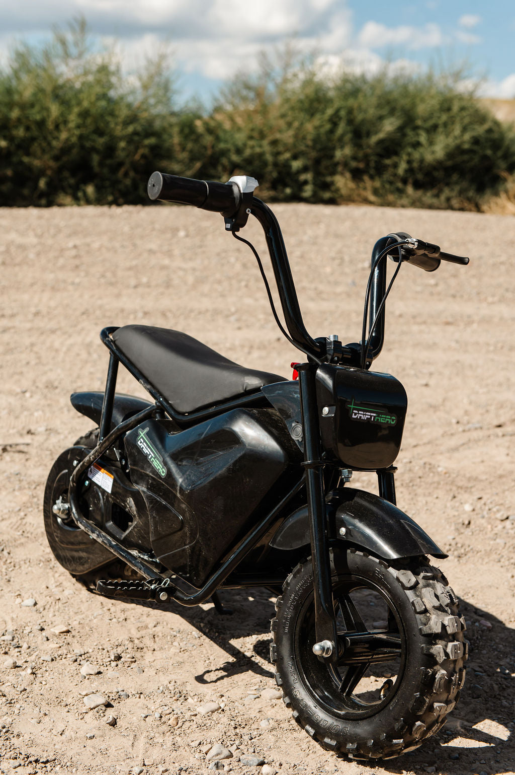 Drift Hero USA 250W Mini Electric Bike on a dirt road with greenery in the background