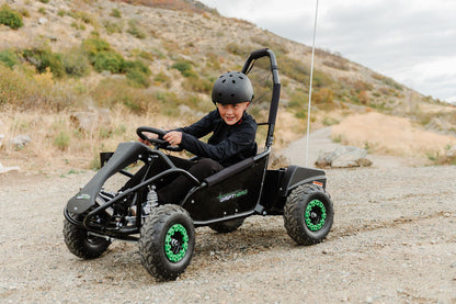 Child driving a Drift Hero USA 1 Seater Electric Go-kart on a dirt road with mountains in the background