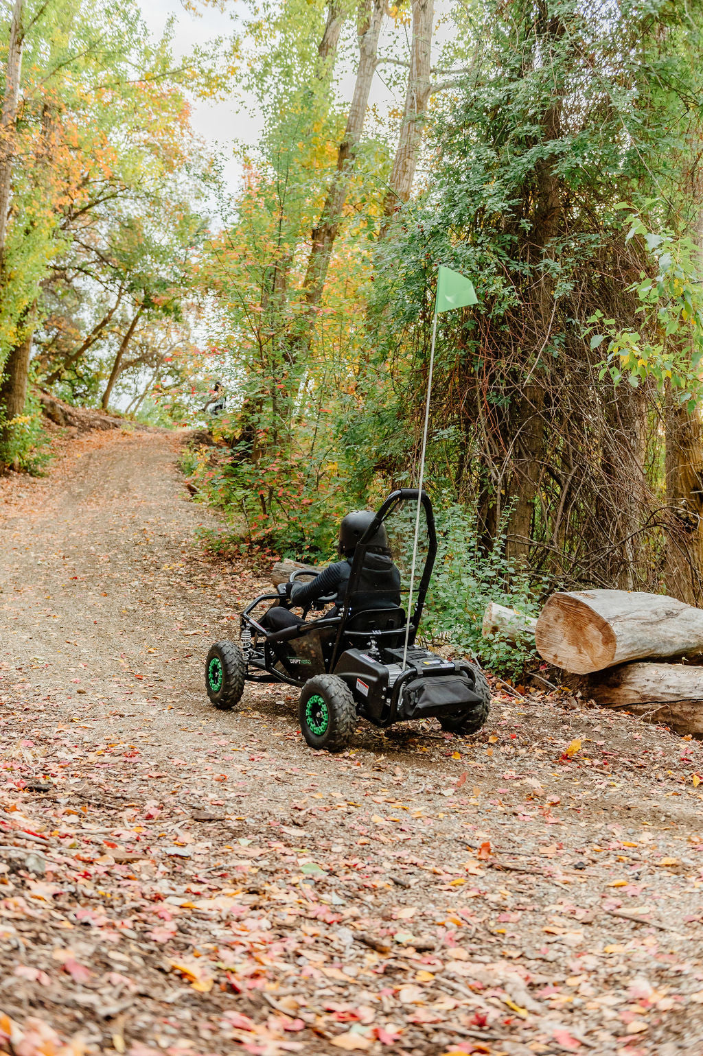 Person riding a Drift Hero USA 1 Seater Electric Go-kart on a forest path with trees and logs in the background