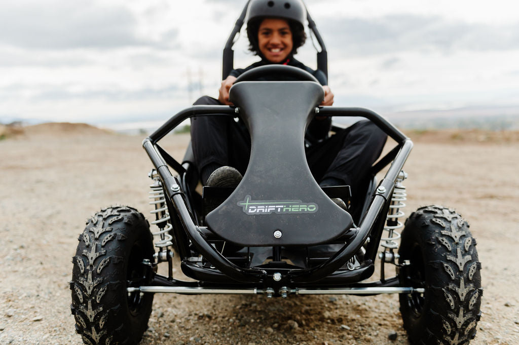 Person driving a Drift Hero USA 1 Seater Electric Go-kart off-road vehicle on a dirt track