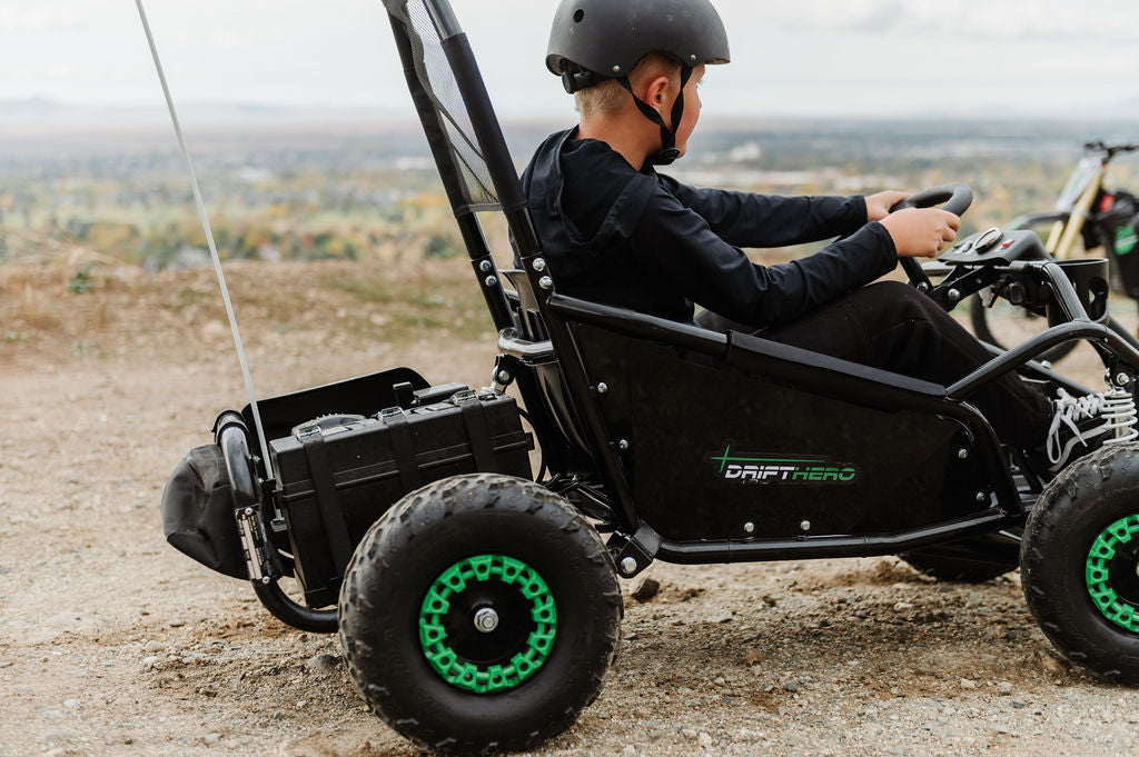 Person driving a Drift Hero USA 1 Seater Electric Go-kart with green accents on a dirt track.