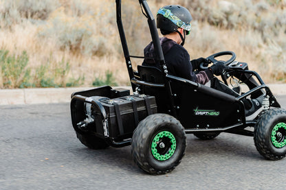 Child driving a Drift Hero USA 1 Seater Electric Go-kart on a paved surface with a natural background.