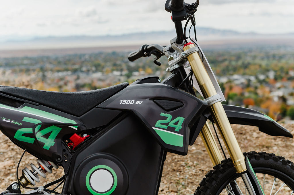 Close-up of a Black Drift Hero USA 1600W Electric Dirt Bike with green accents and the number 24 on a scenic background