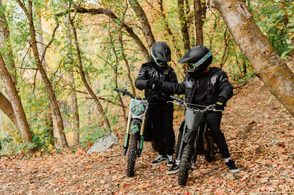 Two people riding Drift Hero USA 1600W Electric Dirt Bike on a forest road