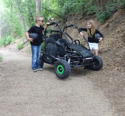 Two people with a Drift Hero USA 2 Seater Electric Go-kart  on a dirt trail in a forest.