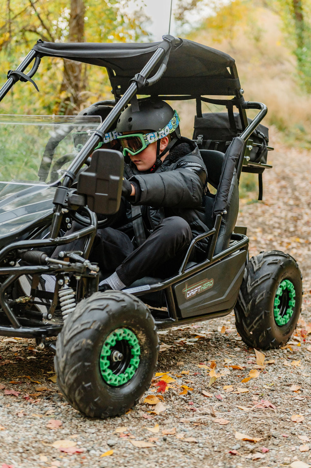 Kidsdriving a Drift Hero USA 2 Seater Electric Go-kart  with green wheels on a  forest trail