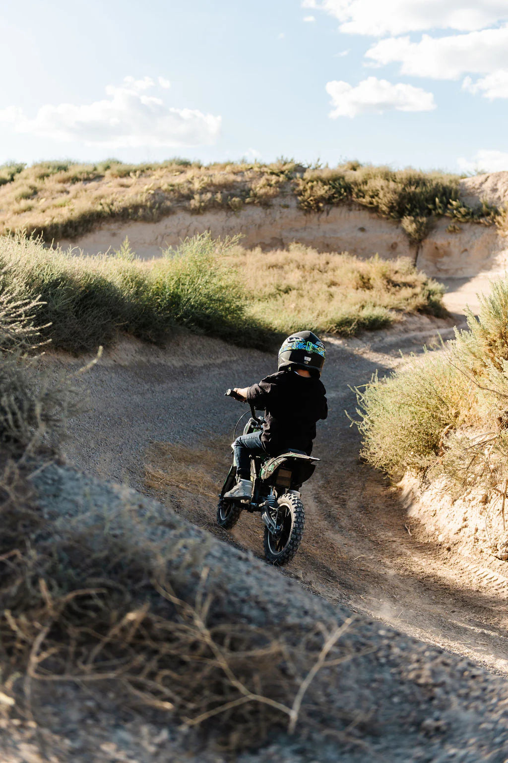 Kid riding a Drift Hero USA 800W Electric dirt bike on a desert trail with a helmet.