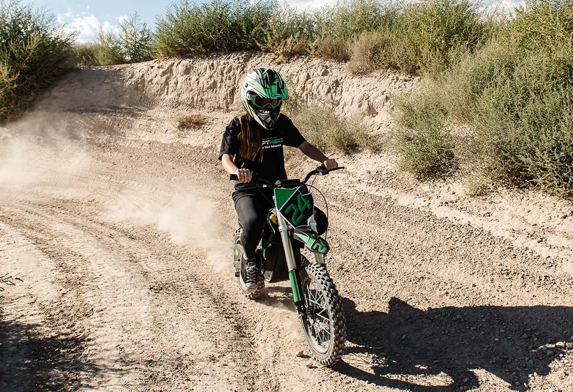 Teen riding a Drift Hero USA 800W Electric dirt bike on a dusty trail in a desert setting