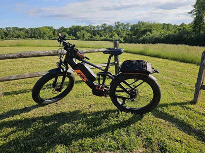 Eunorau Fat-HS electric fat tire bike side profile in grassy field with rear saddlebag attached.
