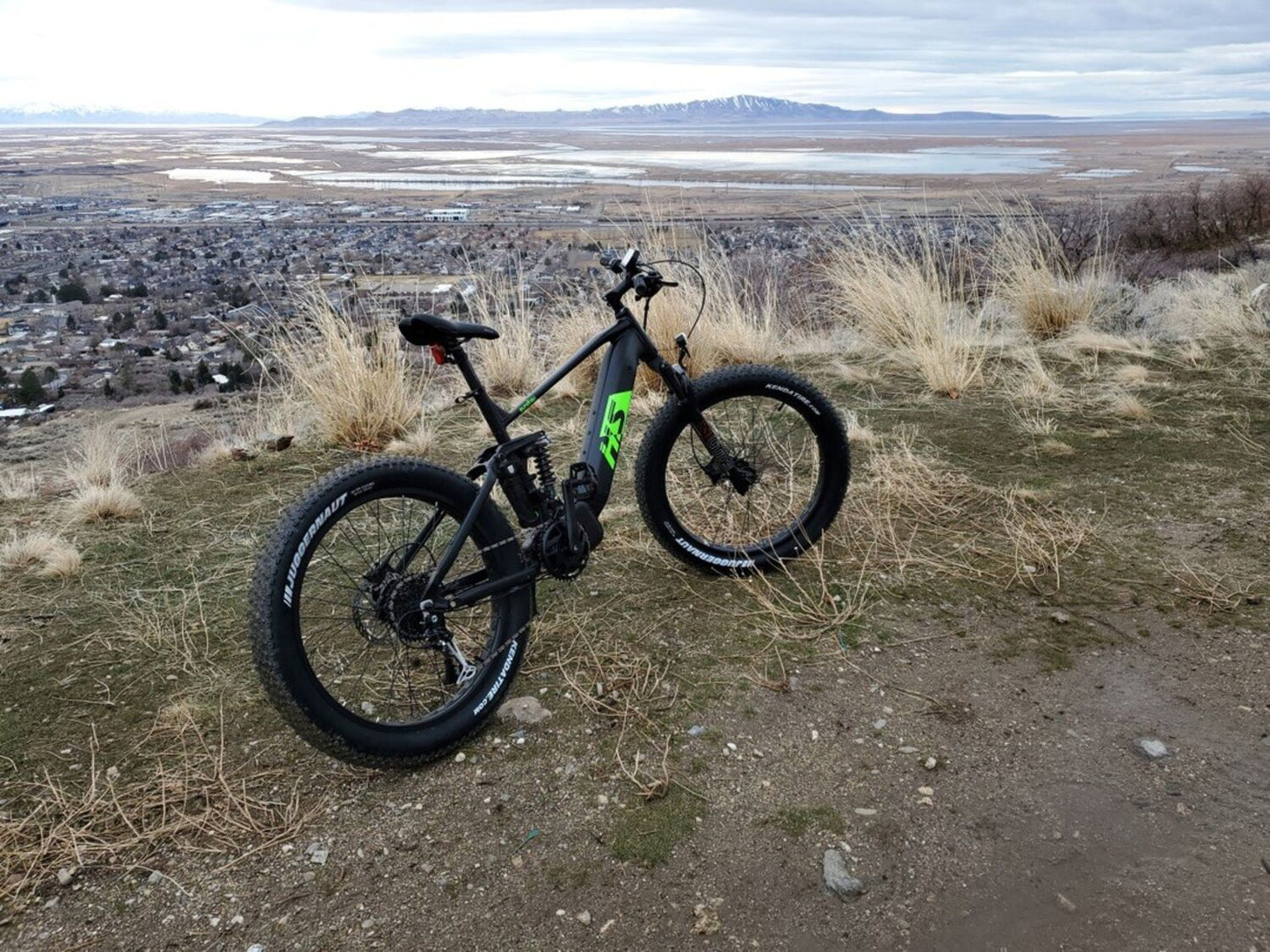 Eunorau Fat-HS electric fat tire bike side profile with rider on forest trail, trees in background.
