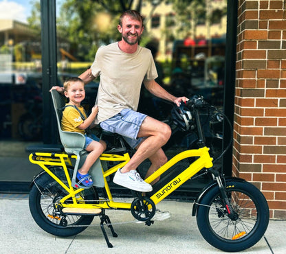 Man and child on a yellow Eunorau G30 Cargo electric bike in front of a brick building