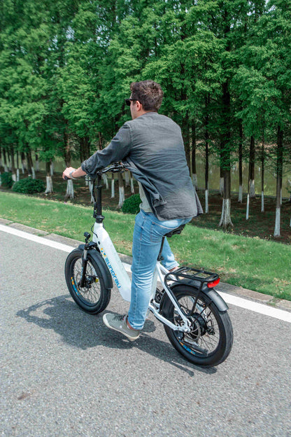 Man riding white EUNORAU META Foldable electric bike with 20-inch wheels on a road surrounded by trees