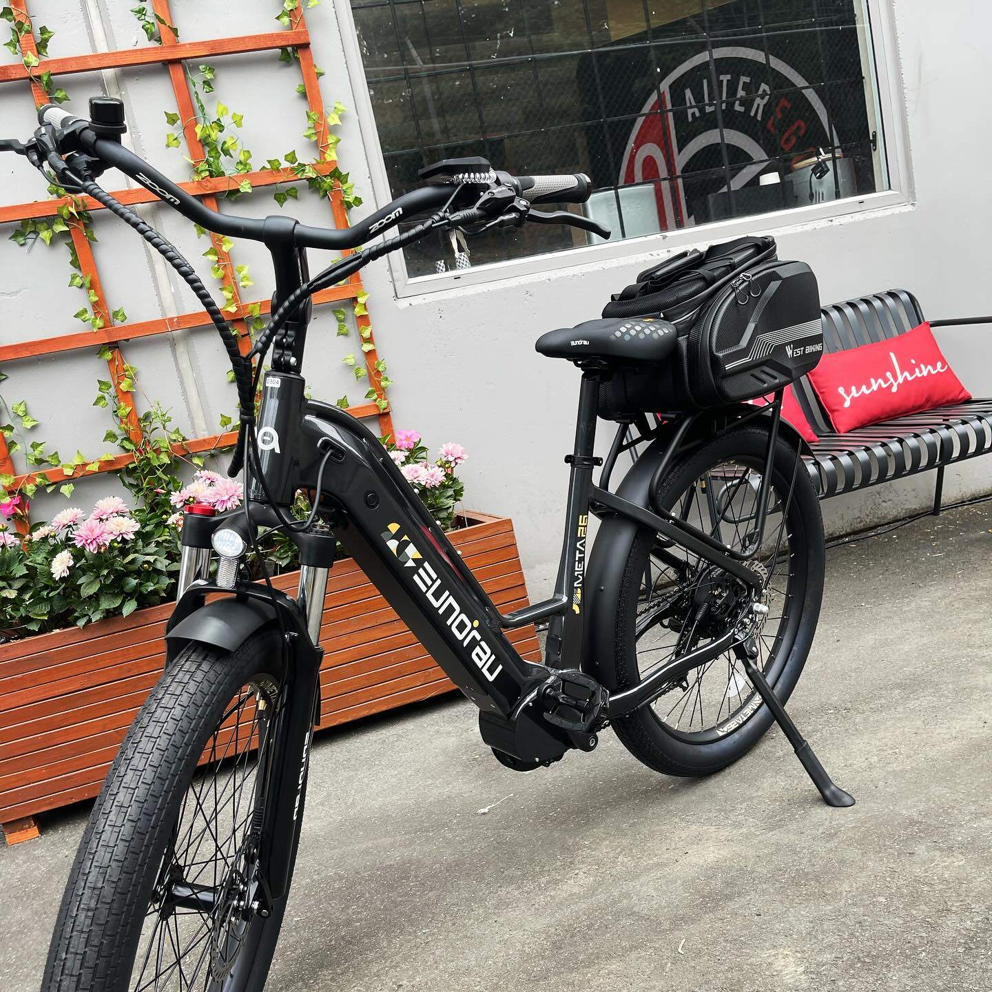 Eunorau Meta 24 ST 2.0 Black Electric bike bicycle parked on a sidewalk with decorative elements in the background