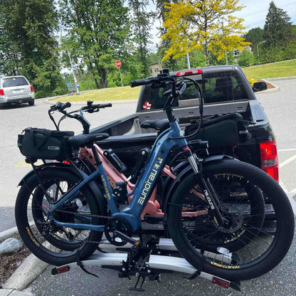 Eunorau Meta 24 ST 2.0 Electric bike  on a bike rack attached to a vehicle in a parking lot with trees and a stop sign in the background.