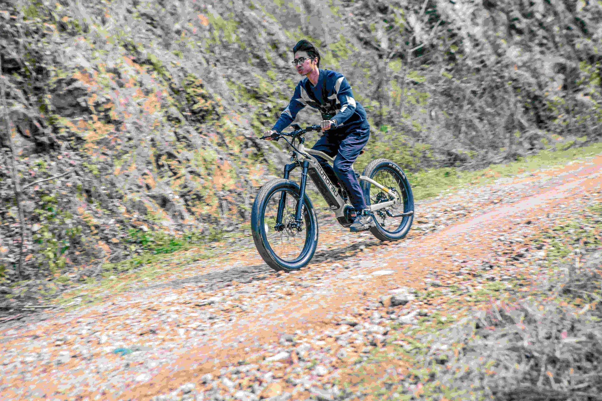EUNORAU Specter-S 3.0 electric fat tire e-bike rider riding off-road on a dirt trail, showcasing the sturdy build and design of the bike.
