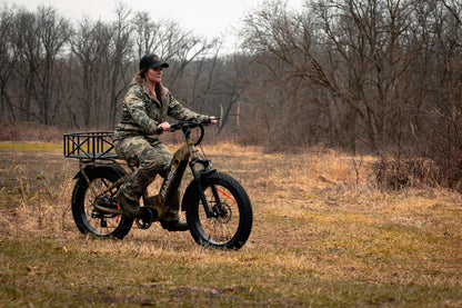 Person riding a Rambo Bikes SAVAGE 2.0 Electric Bike in a field with bare trees in the background