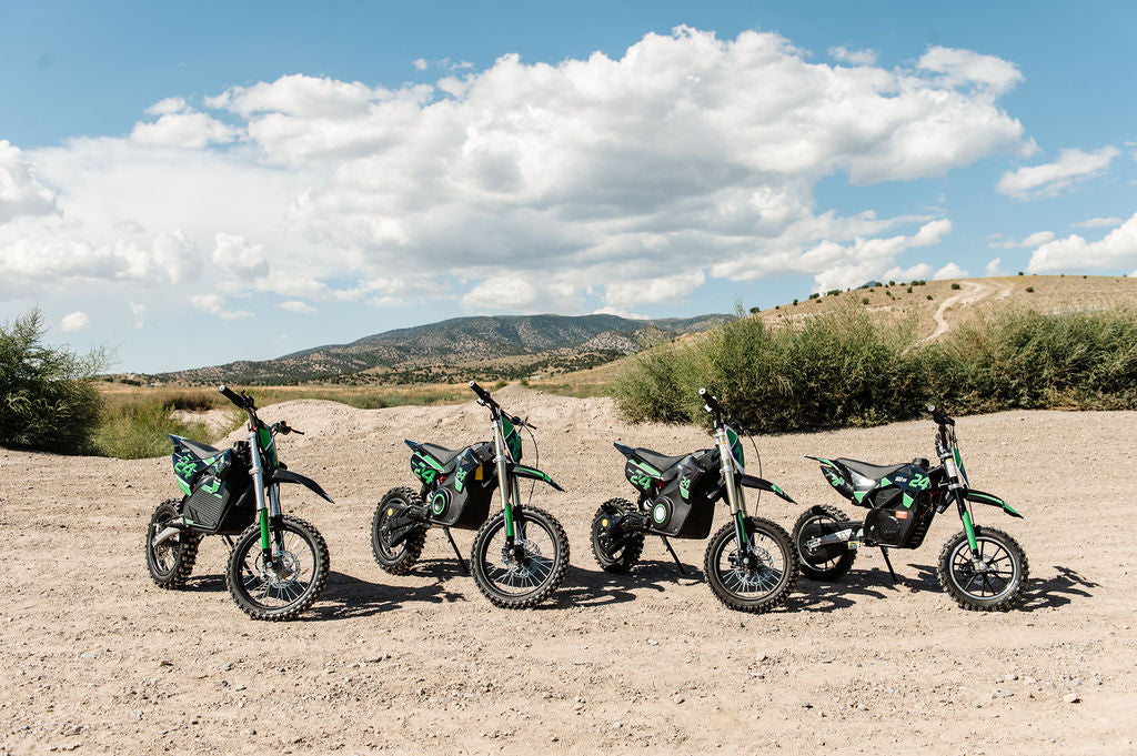 Four Drift Hero USA 2500W Electric Dirt Bike lined up on a dirt road with a scenic background