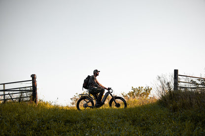 Hunter riding a Rambo Bike Hellcat 2.0 AWD Electric Bike in a field with a fence and open sky