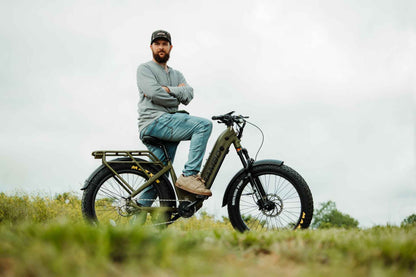 Man sitting on an Rambo Bikes REBEL 2.0 Electric Bike in a grassy field