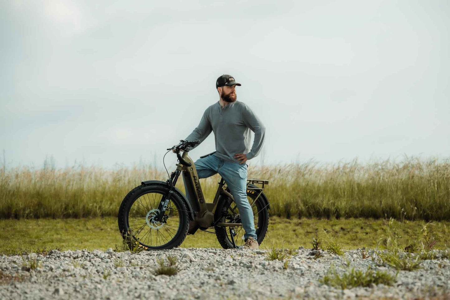 Man sitting on a Rambo Bikes REBEL 2.0 Electric Bike on a gravel road with grass in the background