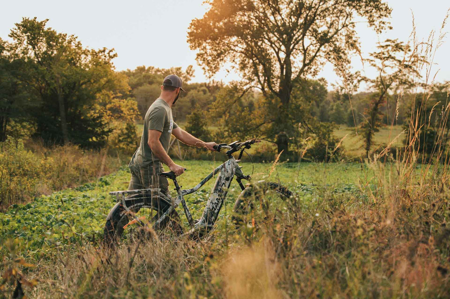 Man with a Rambo Bikes Venom 2.0 Electric Bike in a field with trees in the background