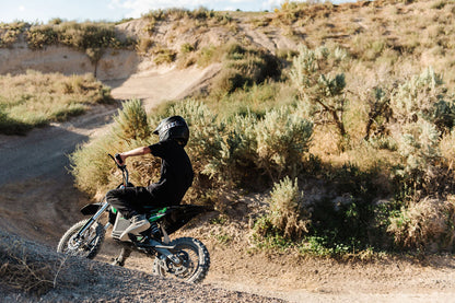 Person with a helmet driving a Drift Hero USA 2500W Electric Dirt Bike on a dusty desert track