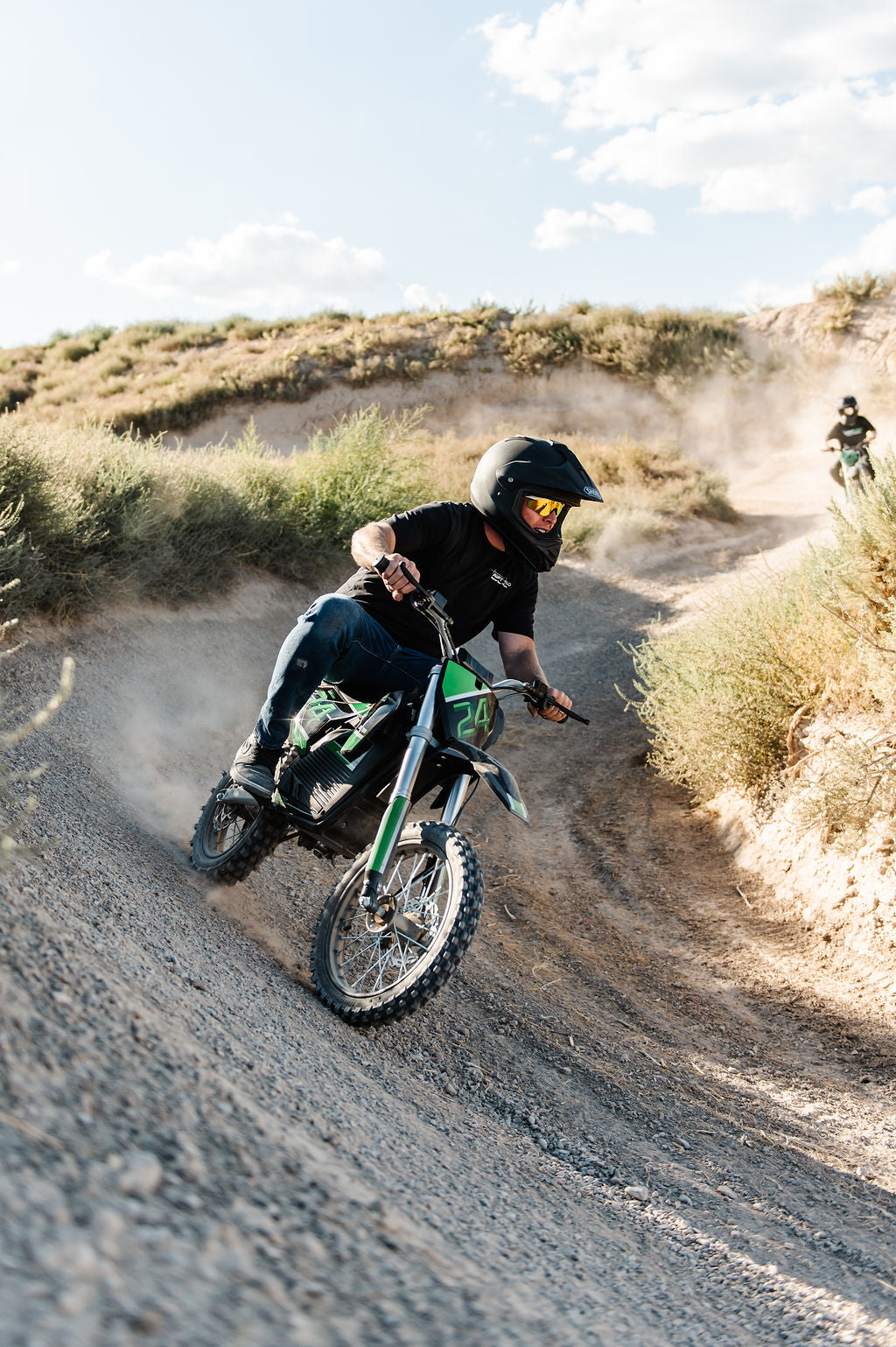 Person riding a Drift Hero USA 2500W Electric Dirt Bike on a dusty trail with a clear sky