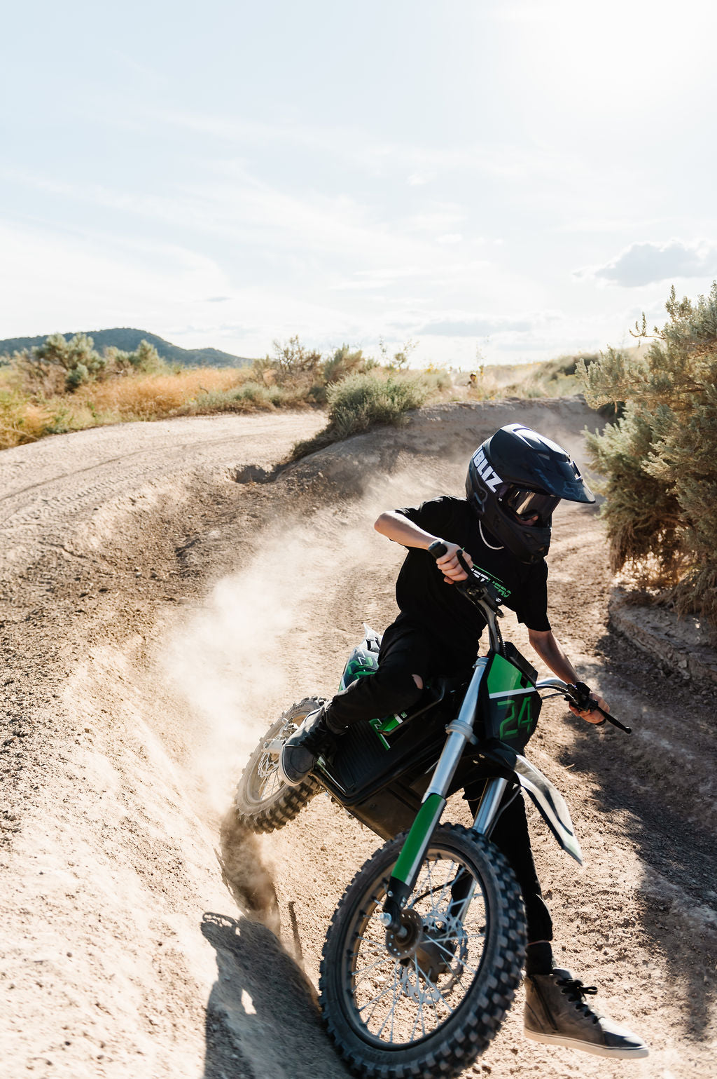 Person riding a Drift Hero USA 2500W Electric Dirt Bike on a dirt road with a scenic background