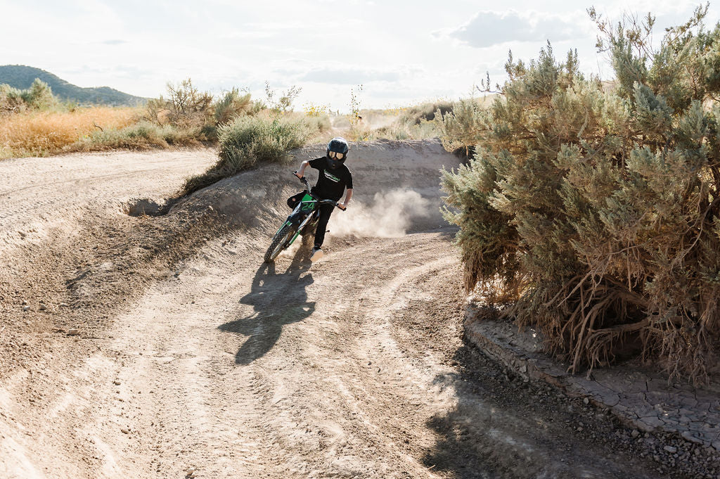Person riding a Drift Hero USA 2500W Electric Dirt Bike on a dirt trail in a desert landscape