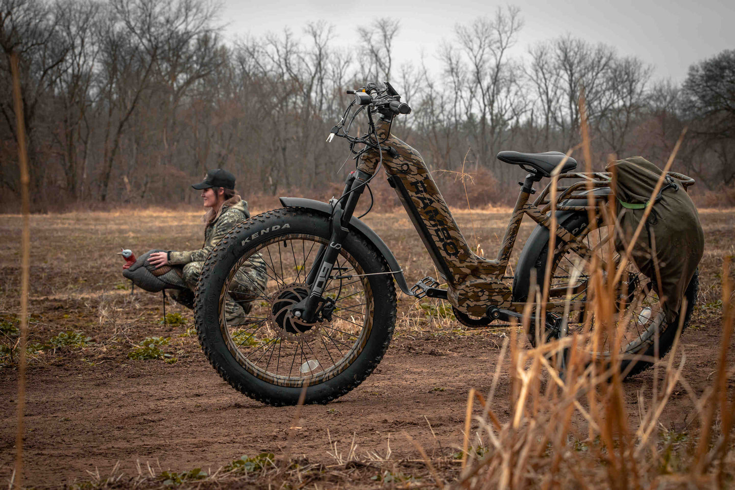 Rambo Bikes Krusader 3.0 All-wheel drive Electric Bike on a dirt trailer with hunter and trees in the background
