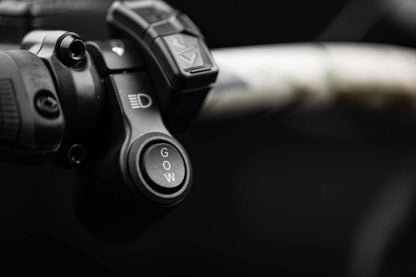 Close-up of a Rambo Bikes Venom 2.0 Electric Bike handlebar with control buttons on a blurred background