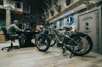 Two Rambo Bikes Venom 2.0 Electric Bike in a room with hunting decor and people sitting at a table.