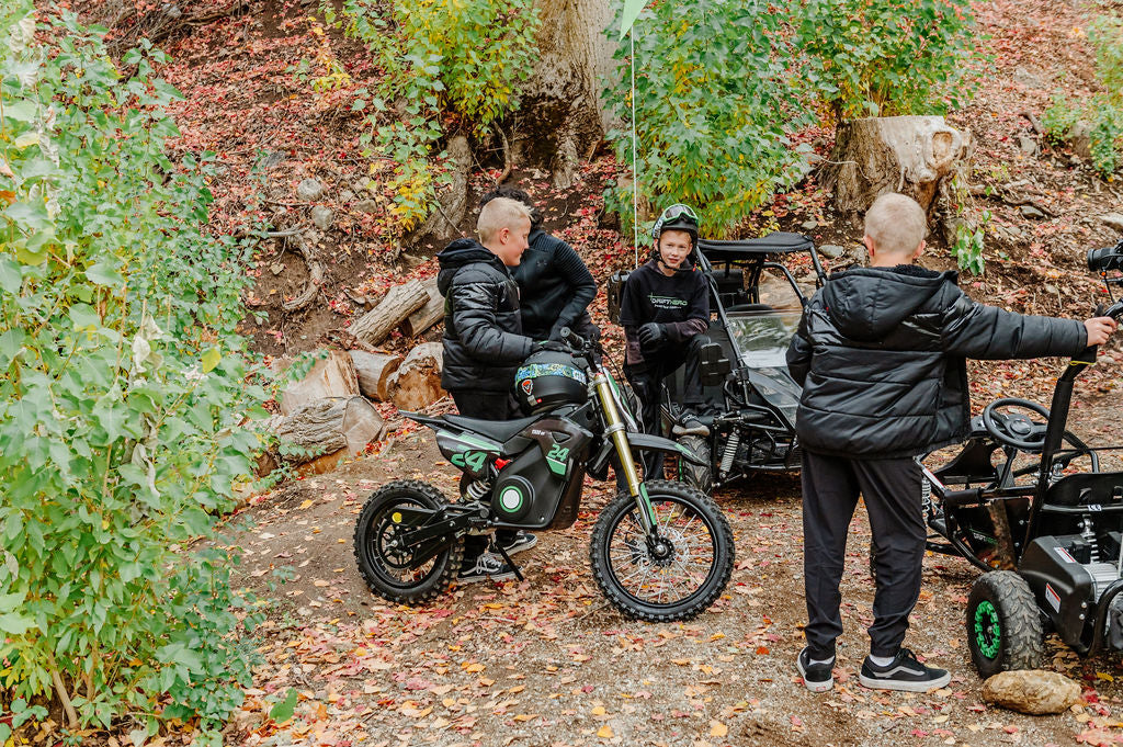 Three people with Drift Hero USA 1600W Electric Dirt Bike in a forest setting