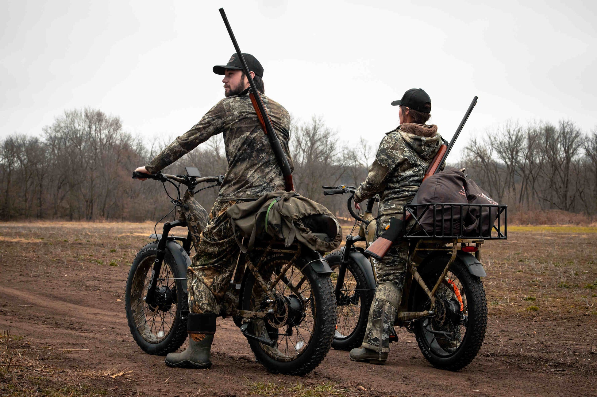 Two hunters rriding a Rambo Bikes Krusader 3.0 All-wheel drive Electric Bike on a dirt trail with trees in the background