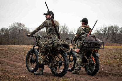 Two hunters rriding a Rambo Bikes Krusader 3.0 All-wheel drive Electric Bike on a dirt trail with trees in the background