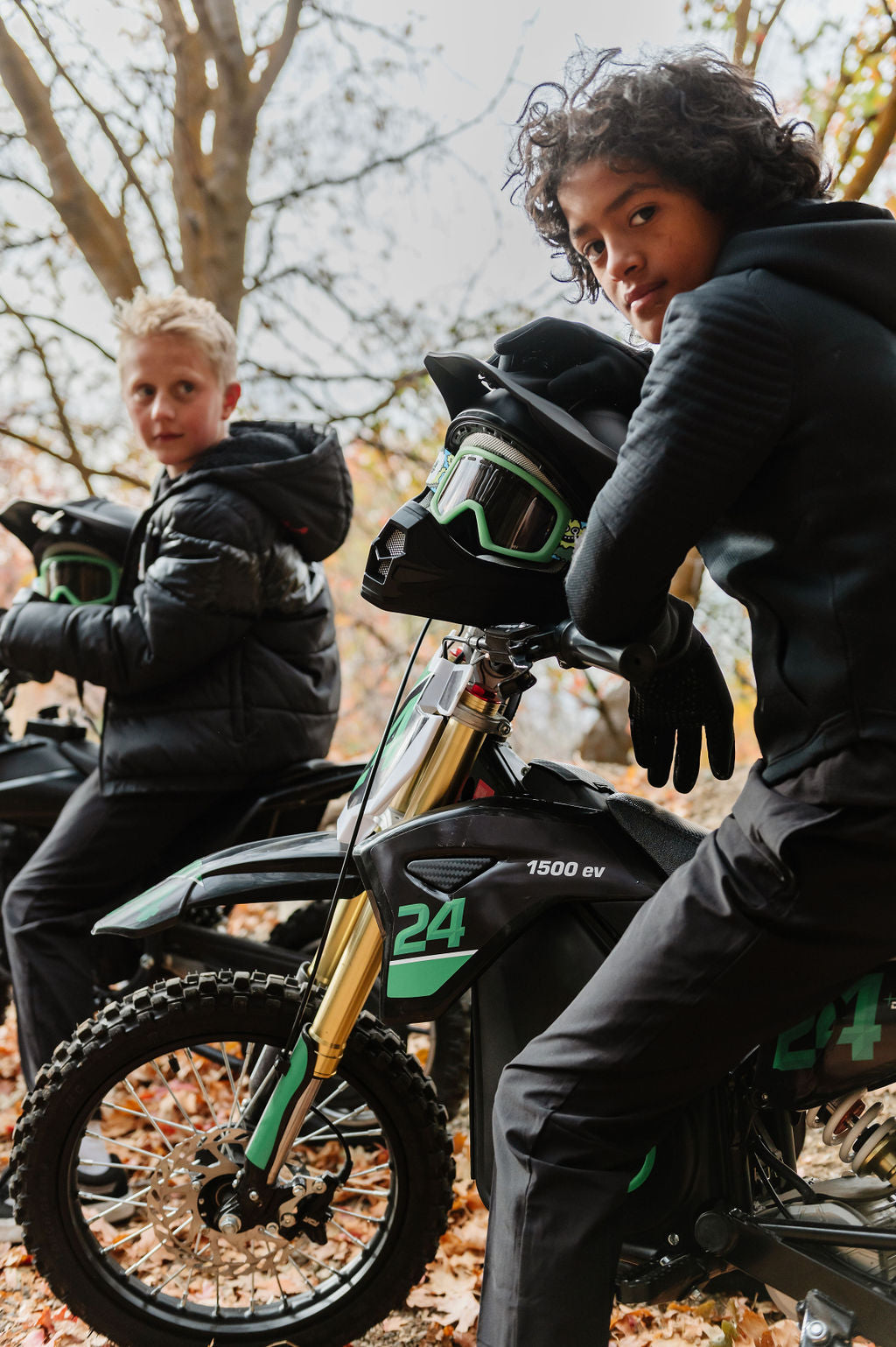 Two children on Drift Hero USA 1600W Electric Dirt Bike in a forest setting