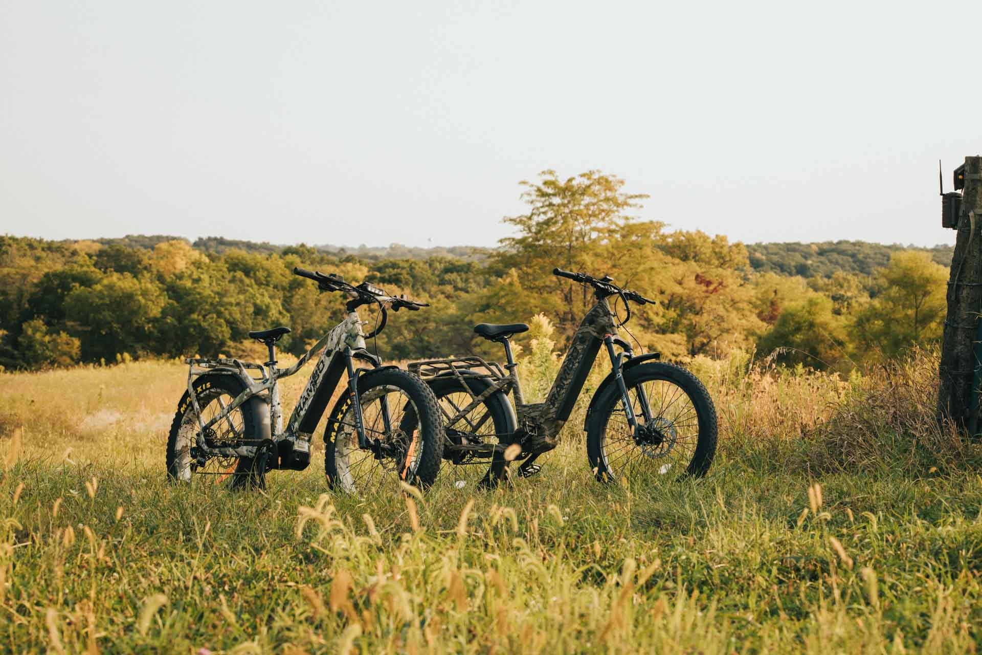 Two Rambo Bikes Venom 2.0 Electric Bike parked on a grassy field with trees in the background
