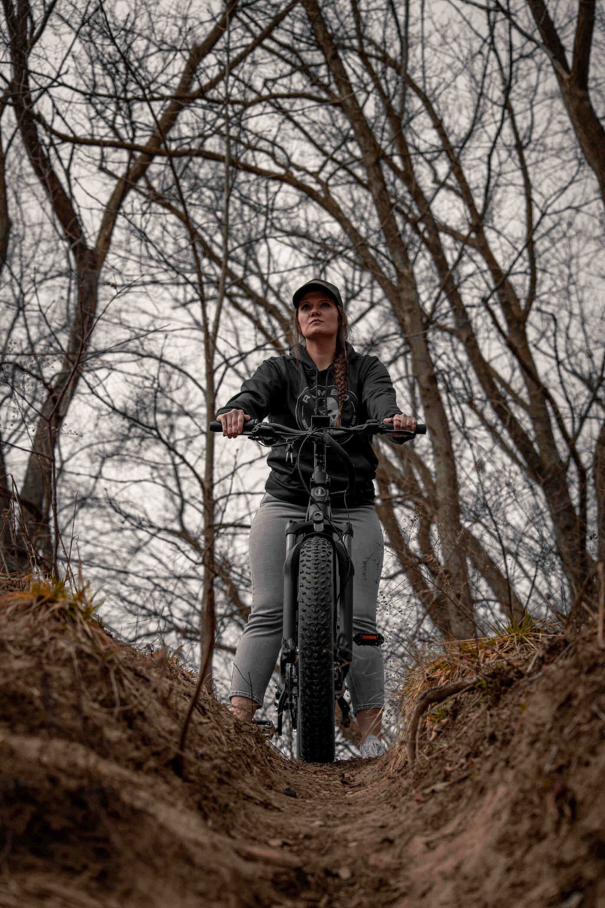 Person riding a Rambo Bikes SAVAGE 2.0 Electric Bike through a forest with bare trees