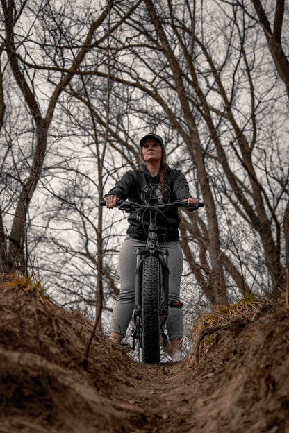 Person riding a Rambo Bikes SAVAGE 2.0 Electric Bike through a forest with bare trees